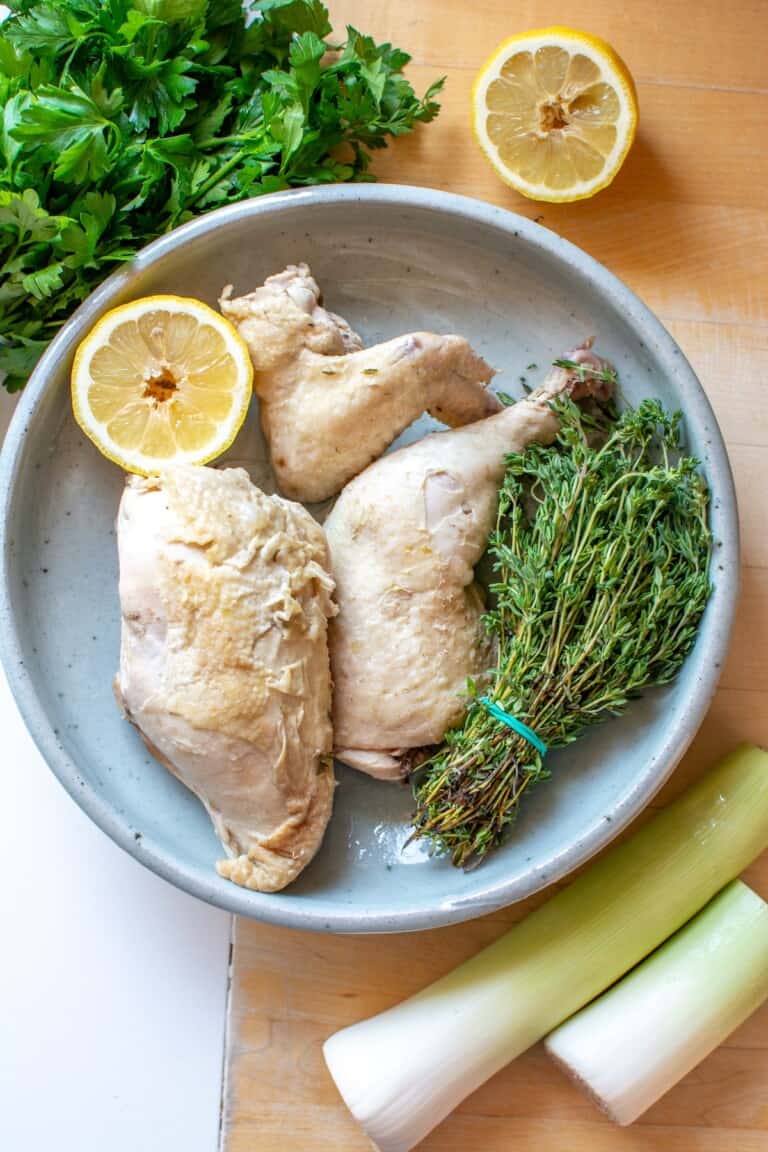 poached chicken on a platter with a bunch of thyme