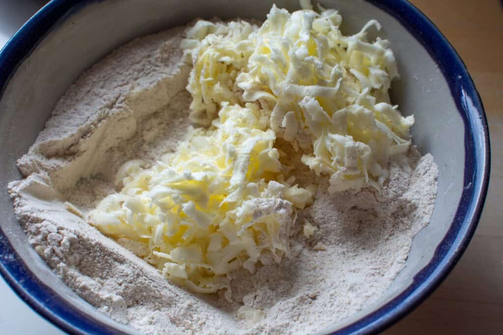 a pile of shredded butter in a bowl with flour