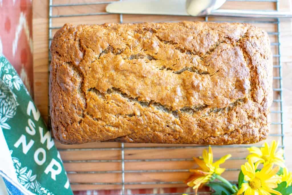 banana bread on a wire rack with yellow flowers