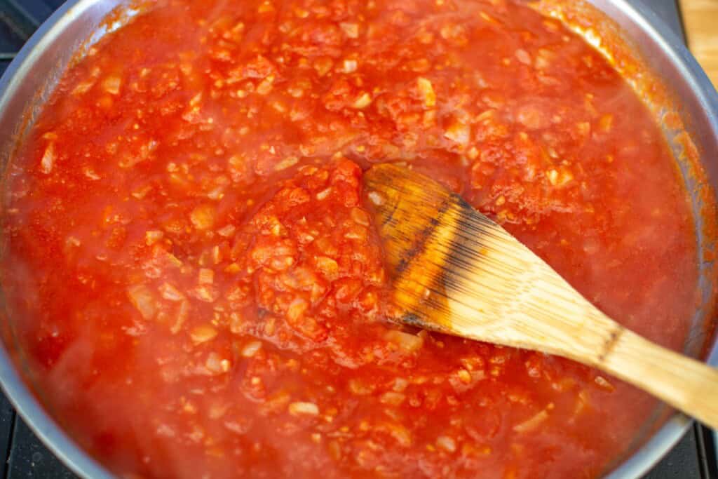 tomato sauce in a skillet with a wooden spoon