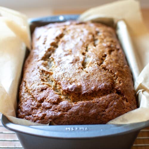 banana bread in a pan on a wire rack