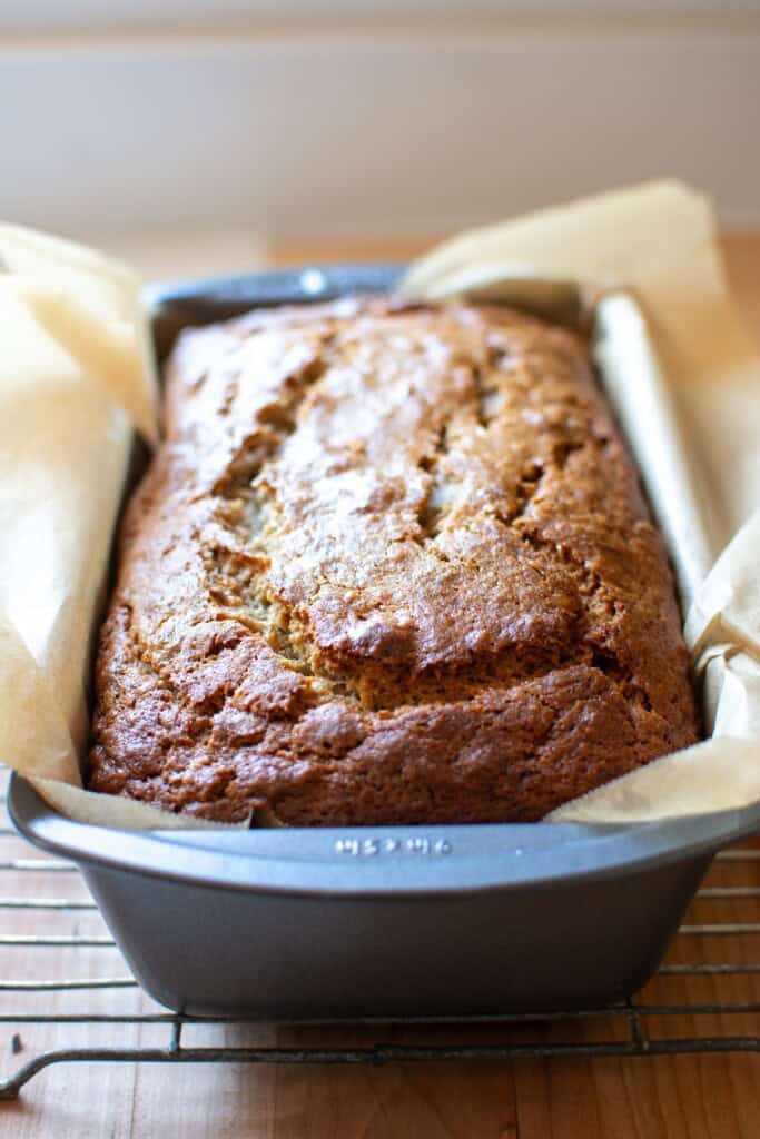 banana bread in a pan on a wire rack