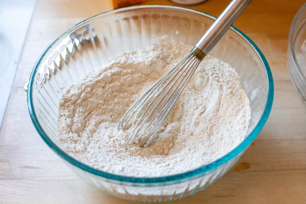 The dry ingredients in a glass bowl with a whisk