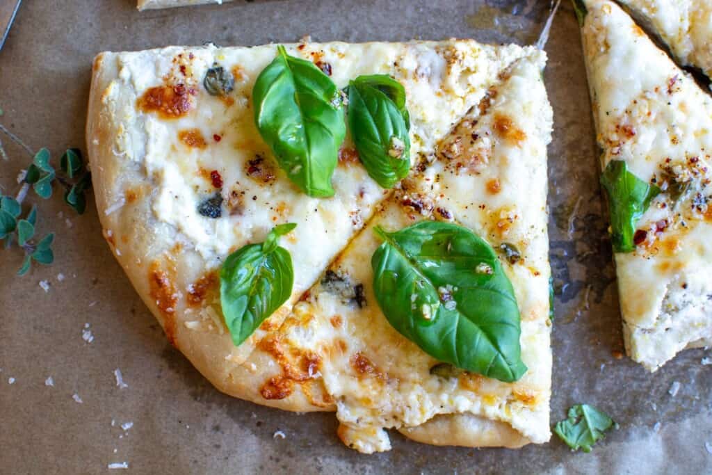 two slices of pizza with basil on top