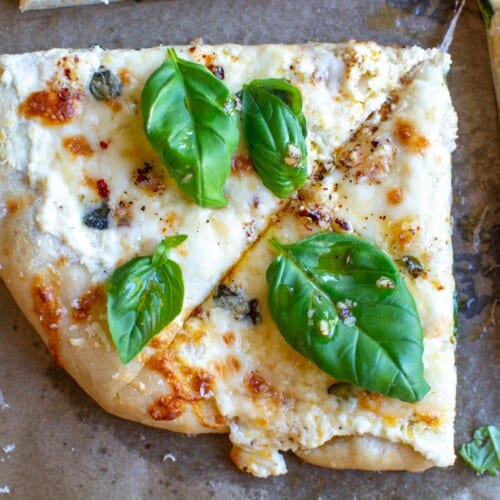 two slices of pizza with basil on top