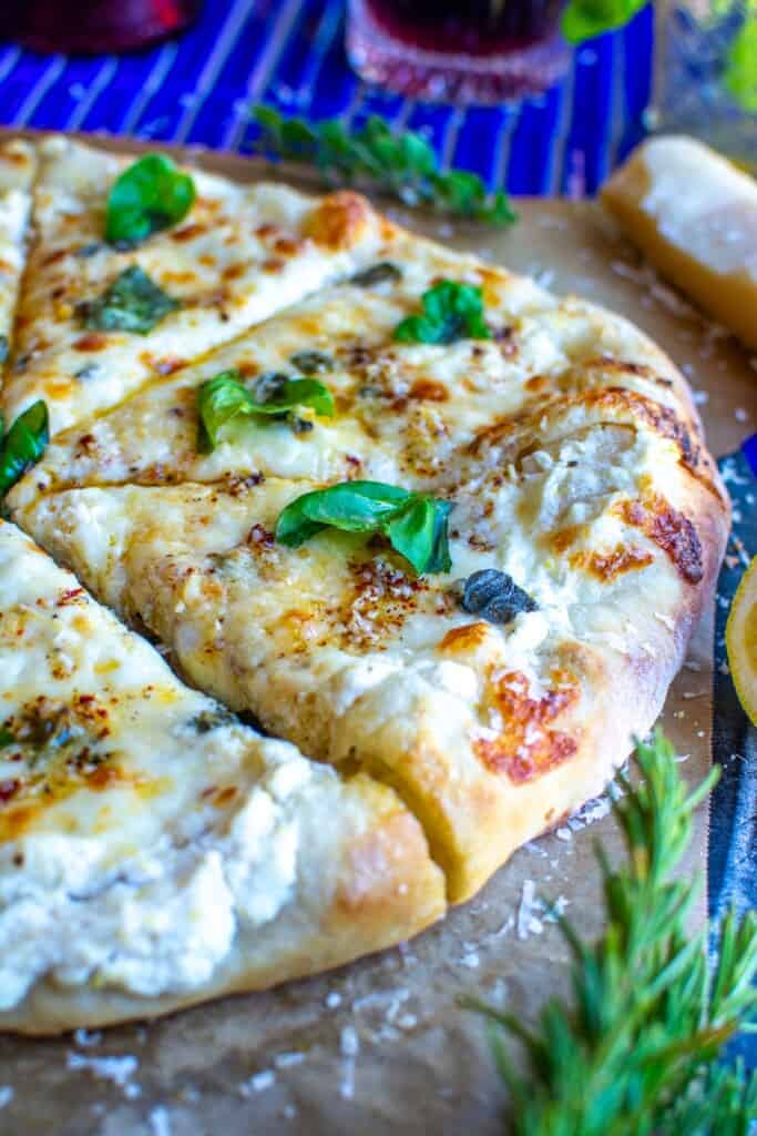 a white pizza cut into slices with basil