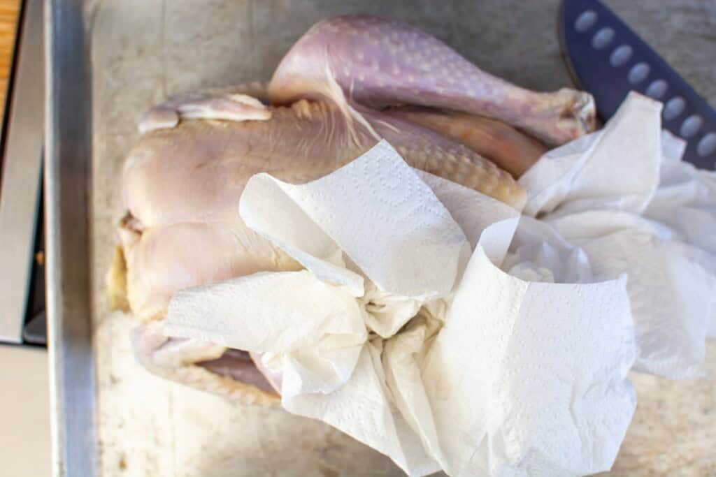 paper towel drying off a whole chicken