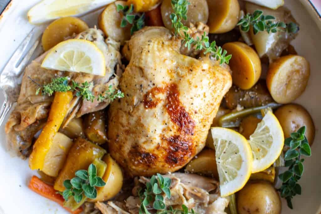 A whole chicken on a platter with vegetables