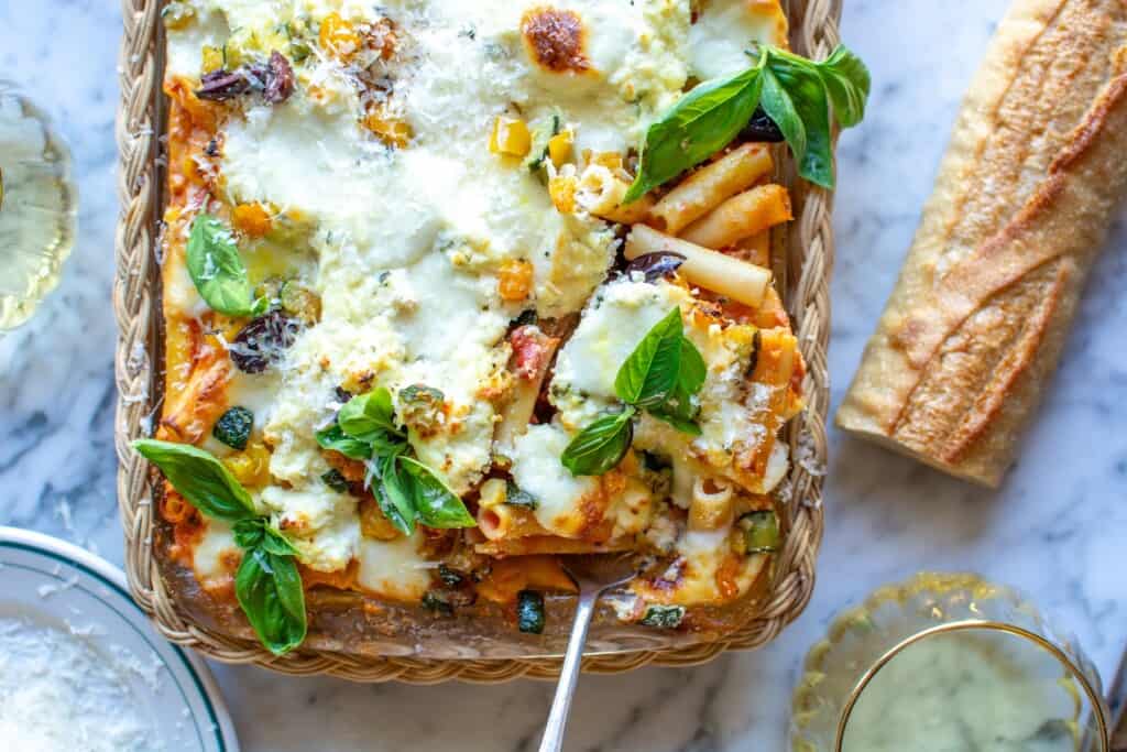 a baking dish with baked ziti topped with basil