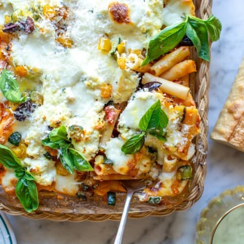 a baking dish with baked ziti topped with basil